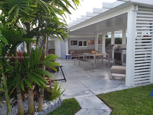 a view of a patio with table and chairs potted plants and large tree