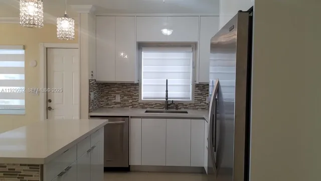 a kitchen with stainless steel appliances granite countertop a sink and a refrigerator