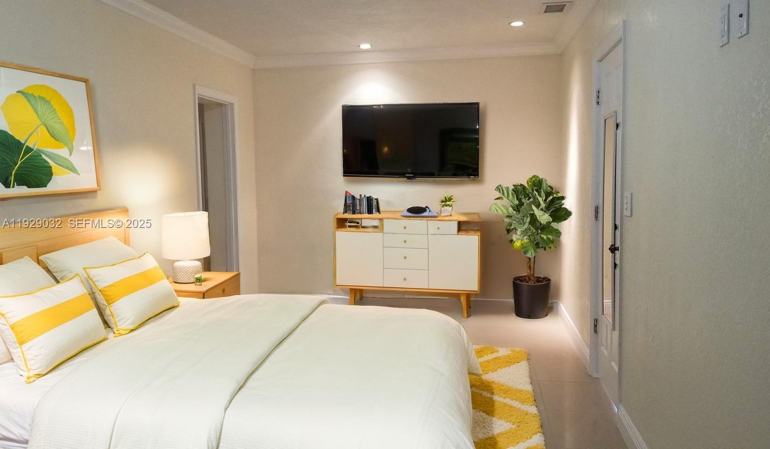 1071 West 66th Street Hialeah, FL 33012 - Photo 9 of 17 a bedroom with a bed and a flat screen tv