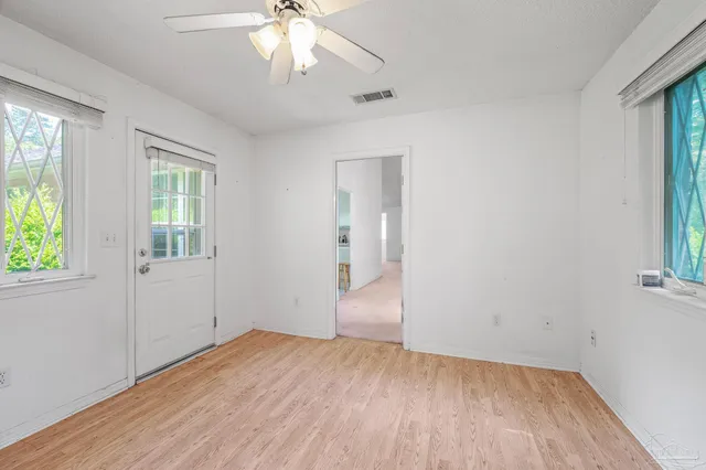 an empty room with wooden floor and windows