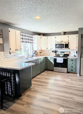 a kitchen with stainless steel appliances granite countertop a stove top oven a sink dishwasher and white cabinets with wooden floor