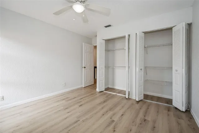 an empty room with wooden floor and a ceiling fan