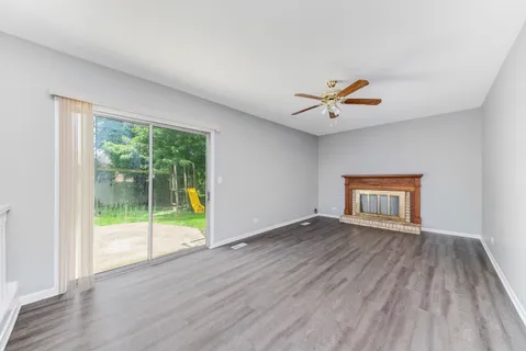 an empty room with wooden floor and a ceiling fan
