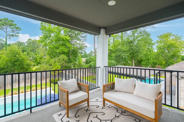 a balcony with wooden floor outdoor seating and trees in the back
