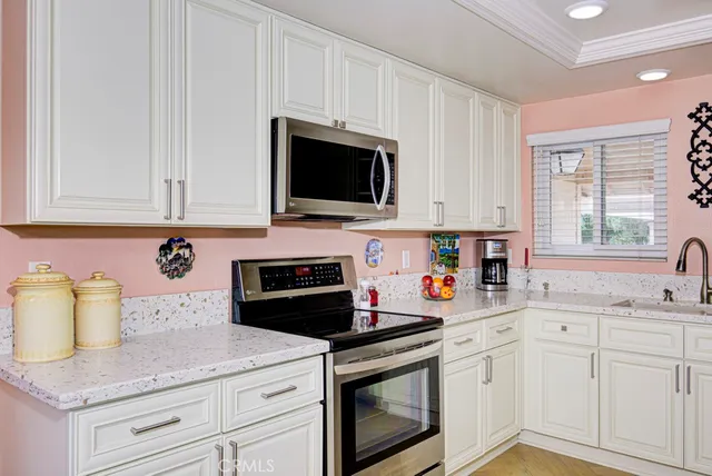 a kitchen with stainless steel appliances white cabinets sink and a window