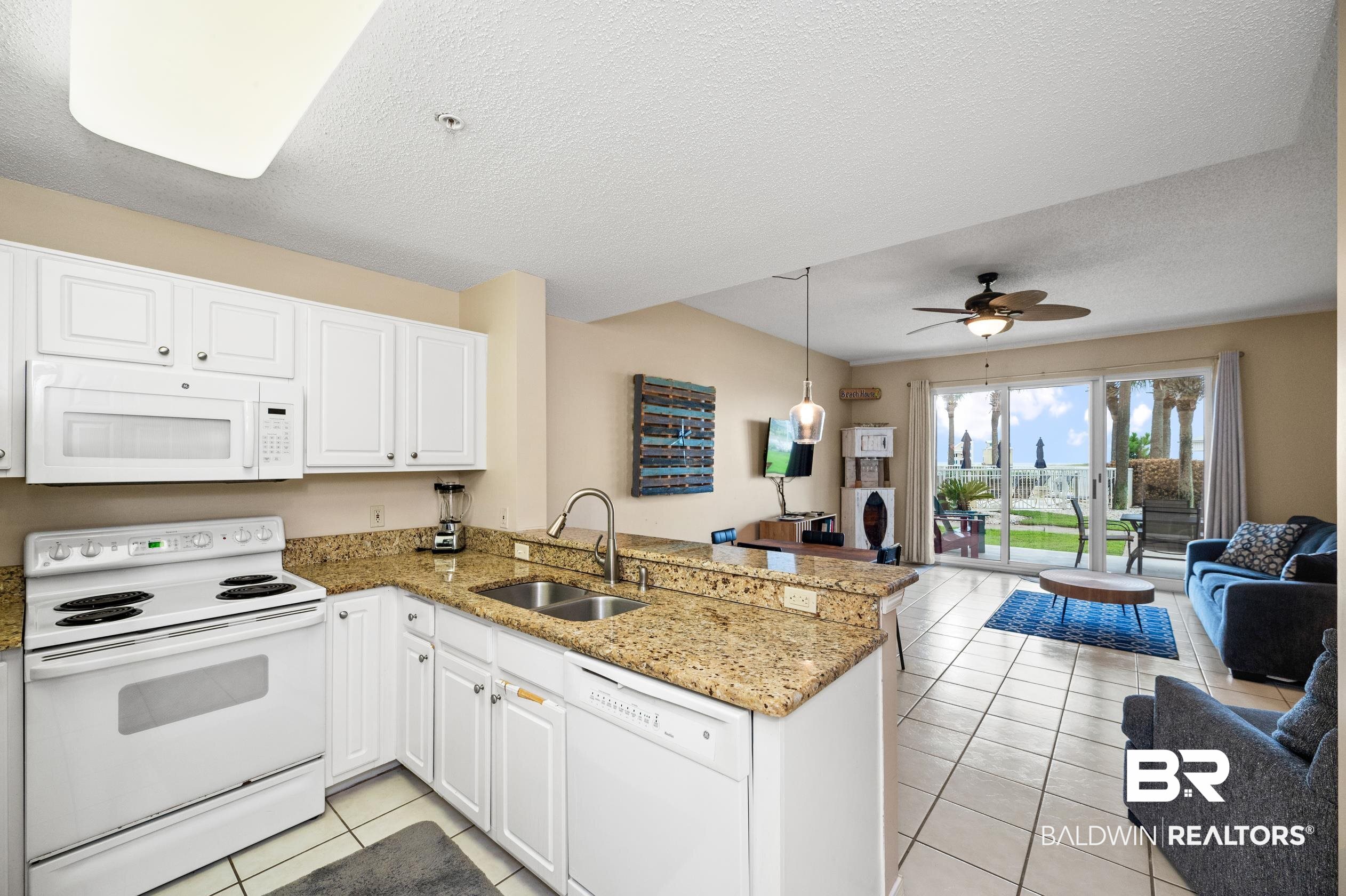 1380 Fort Morgan Road, Unit 106 Gulf Shores, AL 36542 - Photo 19 of 20 Kitchen featuring white appliances, light tile patterned floors, a peninsula, a sink, and open floor plan