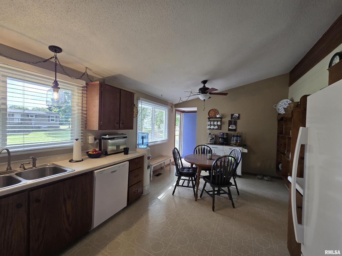 7955 Sugar Grove Road Rushville, IL 62681 - Photo 13 of 28 a kitchen with a refrigerator a sink dishwasher a dining table and chairs with wooden floor