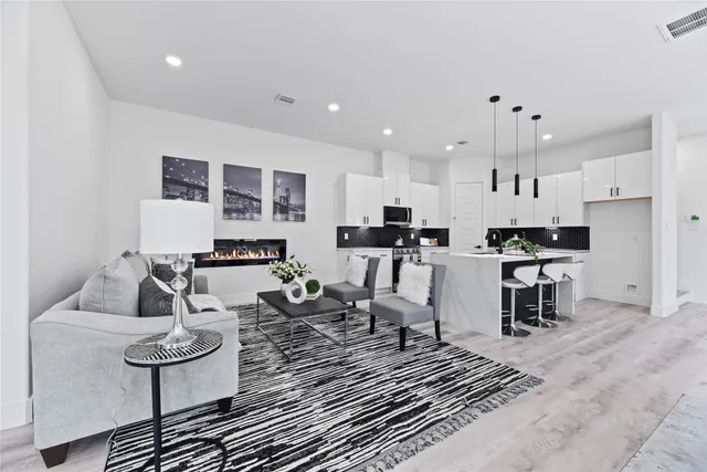 a kitchen with stainless steel appliances kitchen island granite countertop a sink a stove a refrigerator and white cabinets with wooden floor