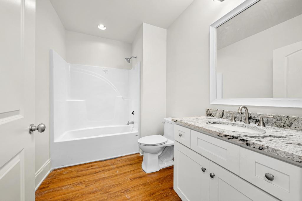 707 Vickery Street Extension Hartwell, GA 30643 - Photo 38 of 50 A pristine bathroom featuring a vanity with granite counters and rich hardwood flooring.