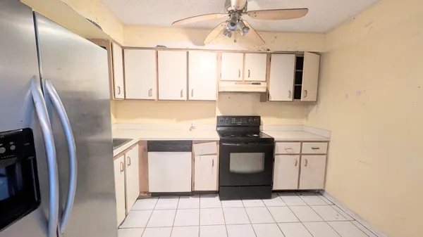 a kitchen with stainless steel appliances granite countertop a refrigerator a stove and white cabinets