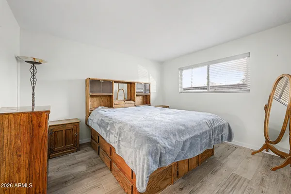 a bedroom with a bed a dresser and windows