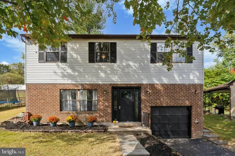 a front view of a house with a yard and a tree