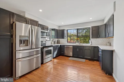 a kitchen with stainless steel appliances a refrigerator a sink cabinets and wooden floor