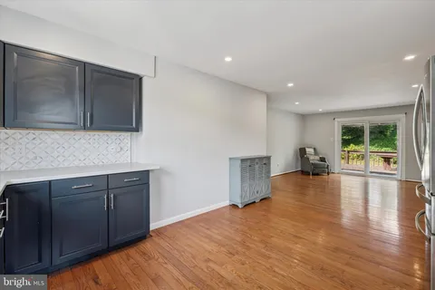 a view of an empty room with wooden floor and a kitchen