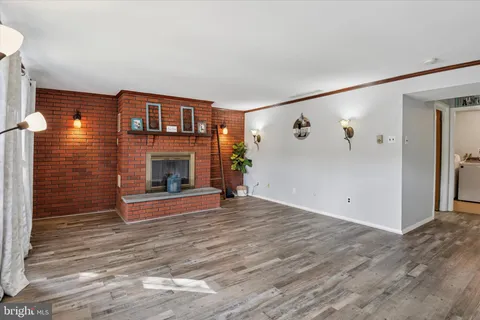 a view of an empty room with wooden floor fireplace and a window