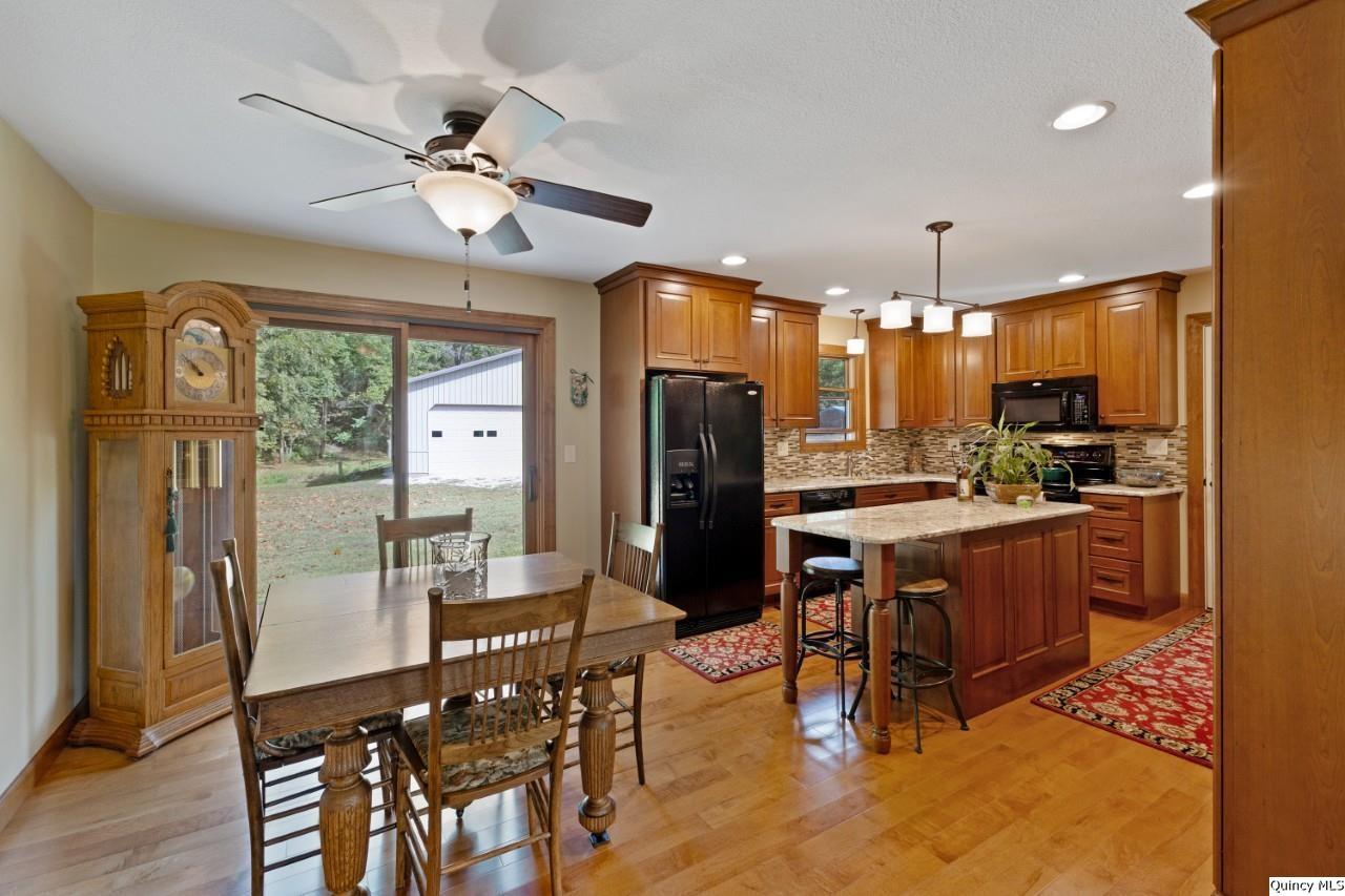8508 Centerville Road Hannibal, MO 63401 - Photo 4 of 36 a kitchen with stainless steel appliances kitchen island granite countertop a refrigerator a stove a dining table and chairs with wooden floor