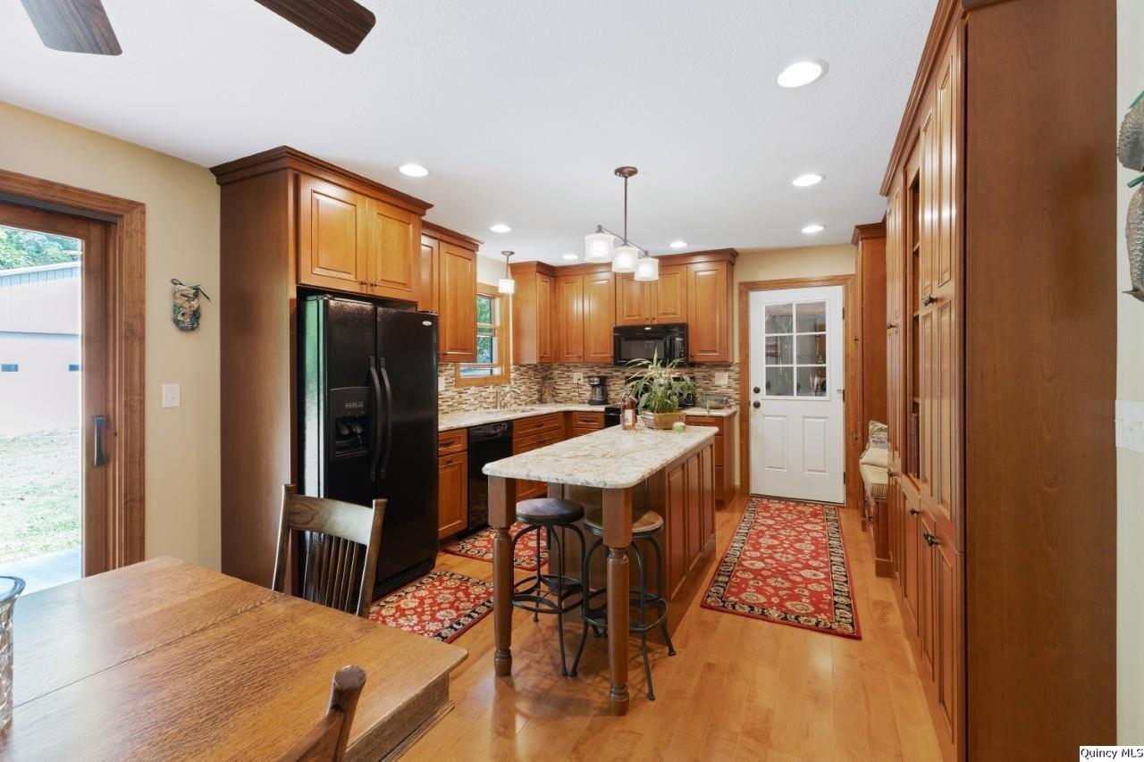 8508 Centerville Road Hannibal, MO 63401 - Photo 5 of 36 a kitchen with stainless steel appliances kitchen island granite countertop a refrigerator a stove a sink a dining table and chairs with wooden floor