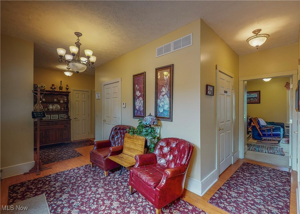 5696 Steubenville Road Southeast Amsterdam, OH 43903 - Photo 4 of 50 Sitting room featuring light wood-type flooring, a textured ceiling, and an inviting chandelier
