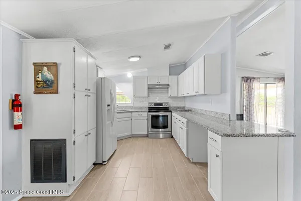 a kitchen with stainless steel appliances granite countertop a refrigerator and a stove top oven