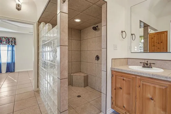 a bathroom with a granite countertop sink a mirror and shower