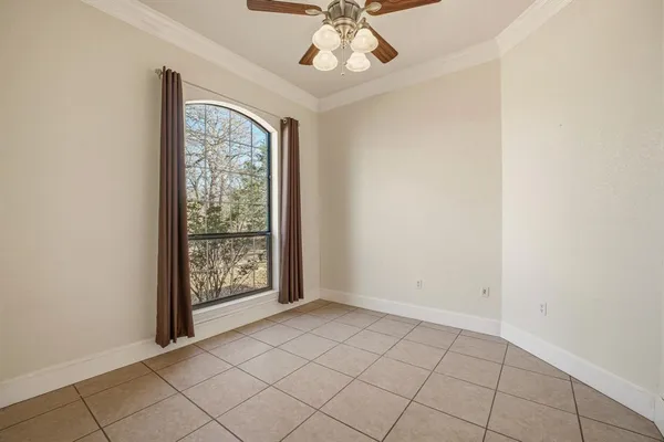 an empty room with windows and chandelier fan