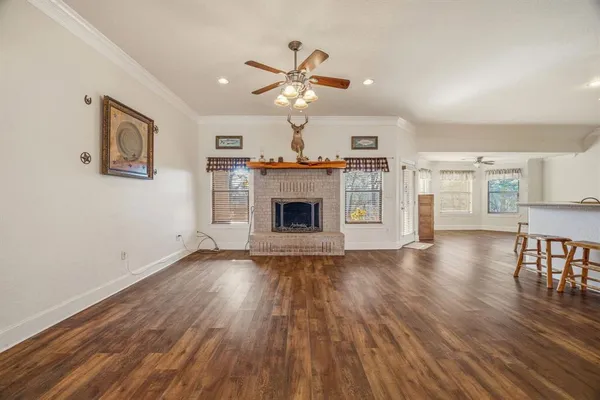 a view of a livingroom with fireplace wooden floor and a ceiling fan
