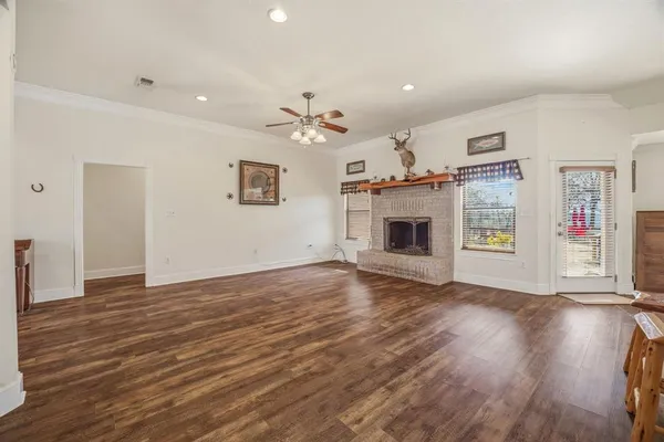 an empty room with wooden floor fireplace and windows