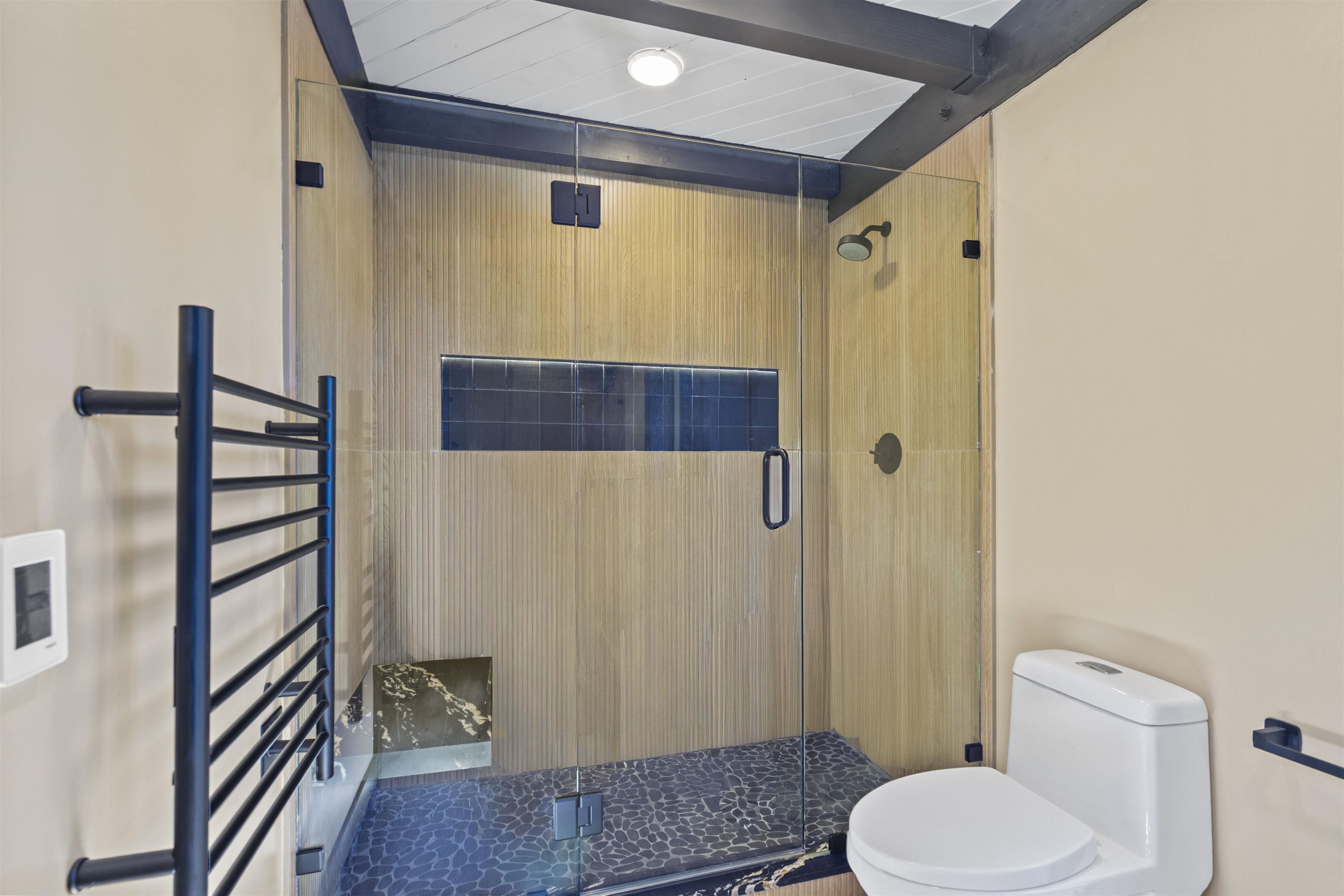 2570 Old Mammoth Road Mammoth Lakes, CA 93546 - Photo 16 of 39 Glass-enclosed shower with wood-finish wall panels, black pebble floor, and integrated niche