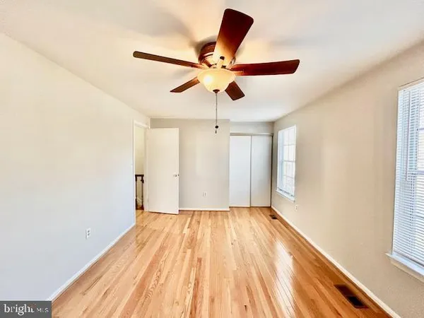 a view of empty room with wooden floor and fan