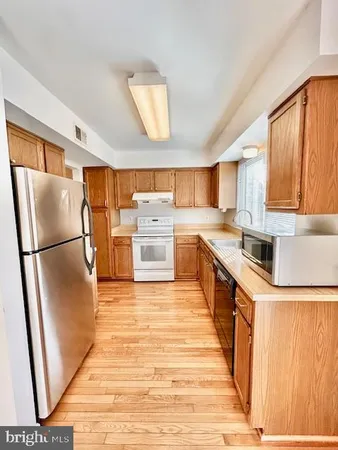 a kitchen with stainless steel appliances granite countertop a refrigerator a stove a sink and a microwave