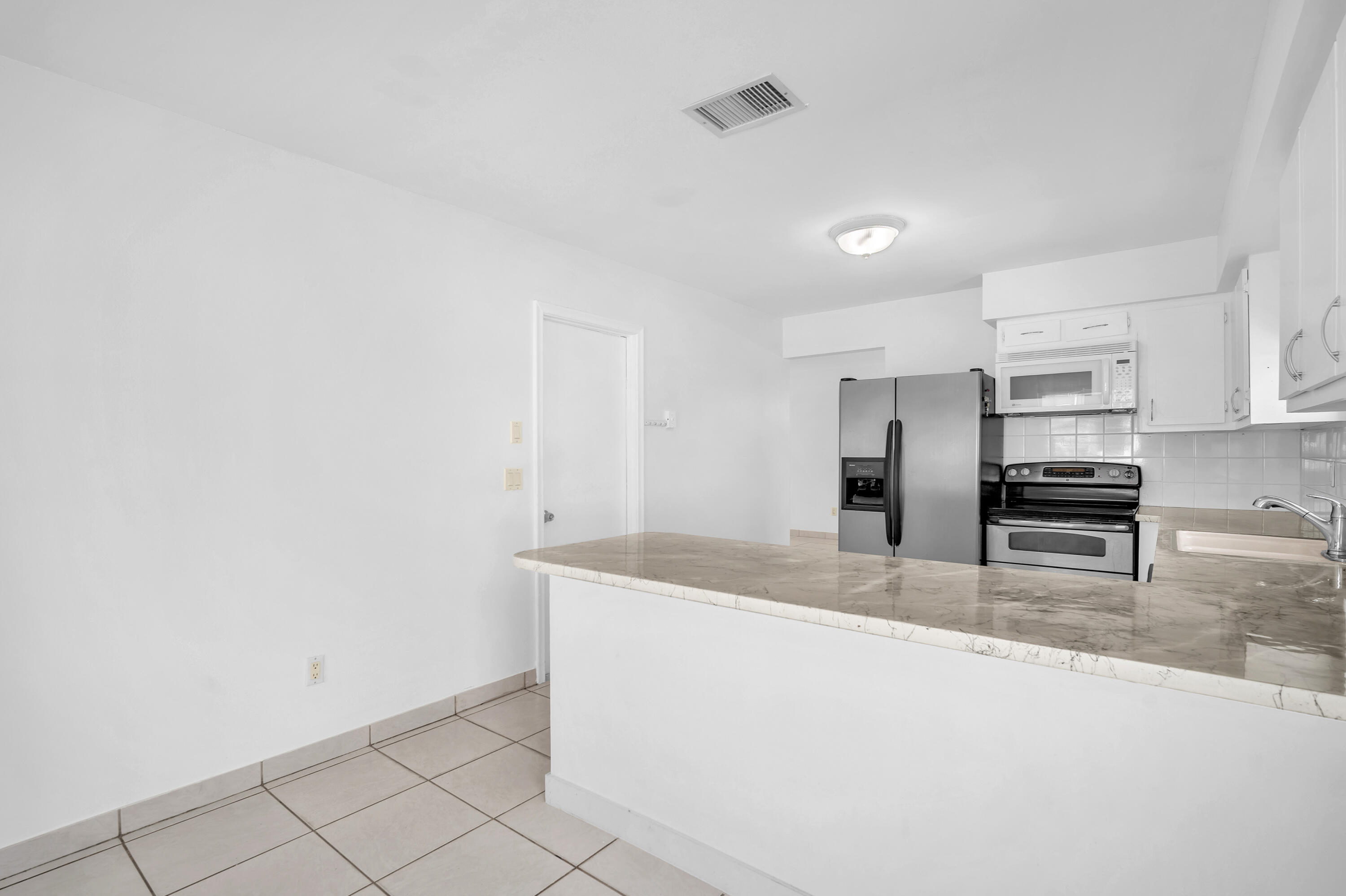10985 Christopher Avenue Boca Raton, FL 33428 - Photo 7 of 24 a kitchen with stainless steel appliances a sink and a refrigerator