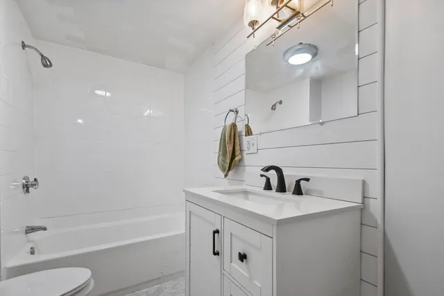 a bathroom with a sink vanity granite toilet tub and shower