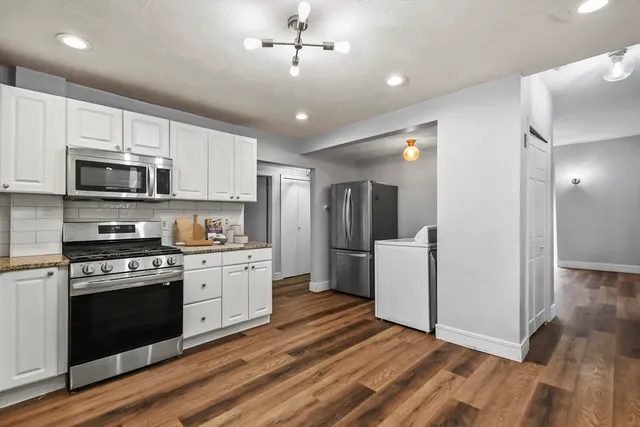 a kitchen with stainless steel appliances a stove top oven a refrigerator cabinets and entryway