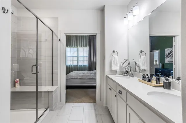a en suite bathroom with a double vanity sink a mirror and a shower