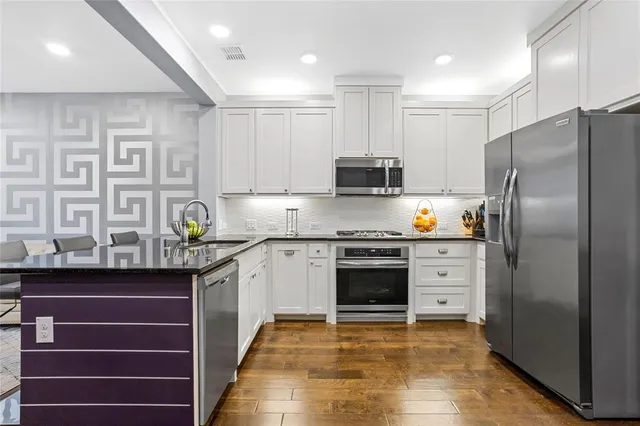 a kitchen with stainless steel appliances granite countertop a refrigerator and a stove top oven