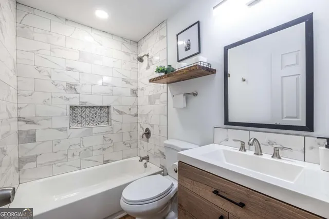 a bathroom with a granite countertop sink toilet a mirror a bathtub and shower