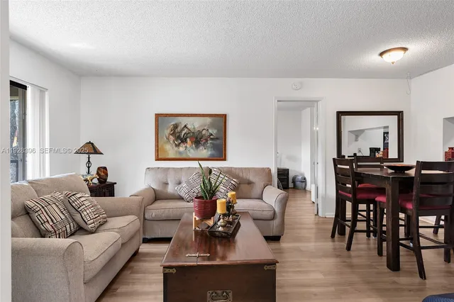 a living room with furniture and a dining table with wooden floor