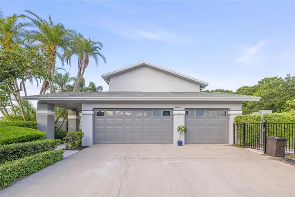 front view of house with a yard and palm trees