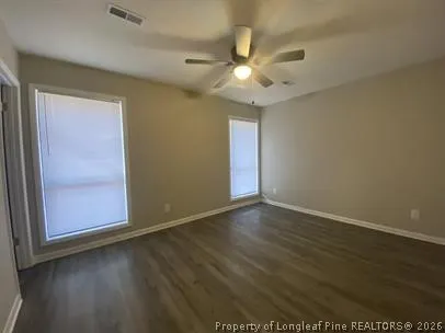 an empty room with wooden floor fan and windows