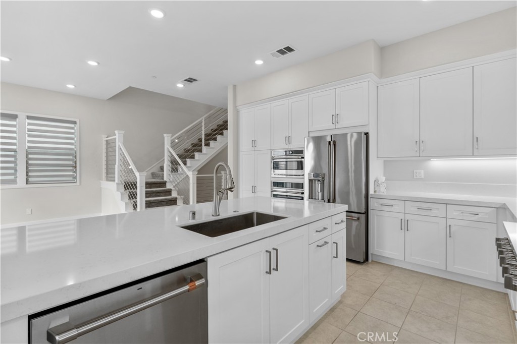 115 Rondo Irvine, CA 92618 - Photo 7 of 28 a kitchen with white cabinets and stainless steel appliances