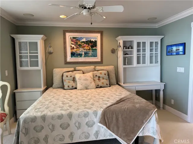 a bedroom with a large bed and a chandelier fan