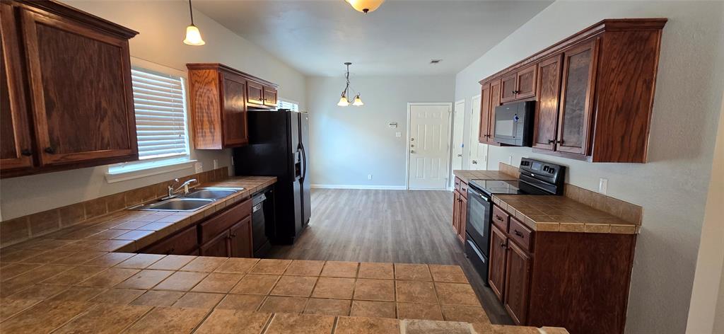2616 South 2nd Street Waco, TX 76706 - Photo 5 of 29 Spacious kitchen featuring rich wood cabinetry, stainless steel appliances, tile countertops, and wood-finish flooring throughout the open layout