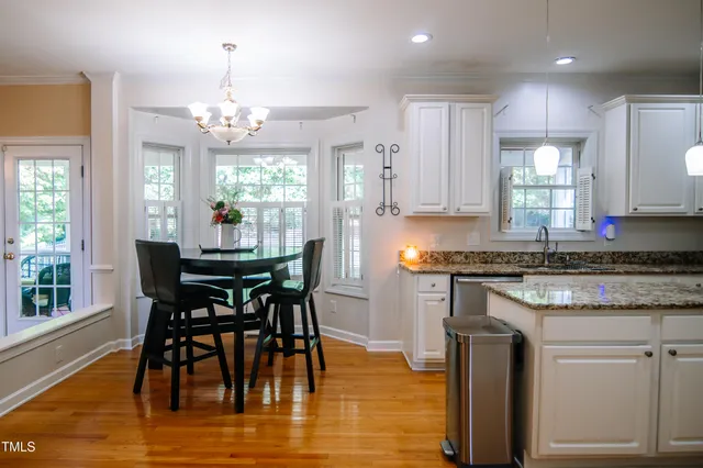 a kitchen with stainless steel appliances granite countertop a stove top oven a sink dishwasher a dining table and chairs with wooden floor