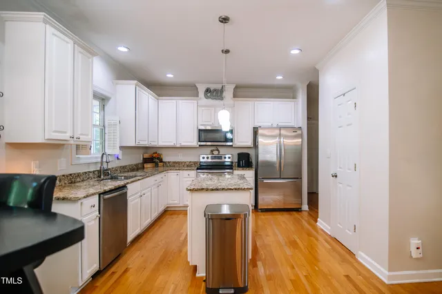 a kitchen with stainless steel appliances granite countertop a refrigerator a stove top oven a sink and cabinets