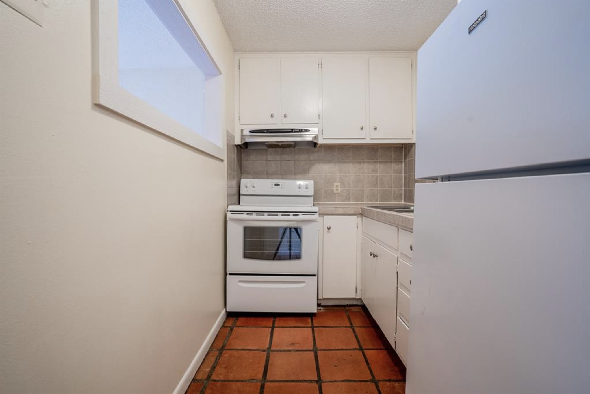 110 East 37th Street, Unit 103 Austin, TX 78705 - Photo 5 of 12 a kitchen with white cabinets and white appliances