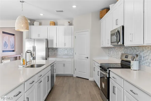 a kitchen that has a lot of white cabinets and stainless steel appliances