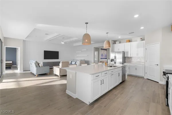 a large white kitchen with a large window a sink and a living room view