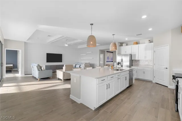 a large white kitchen with a large window a sink and a living room view