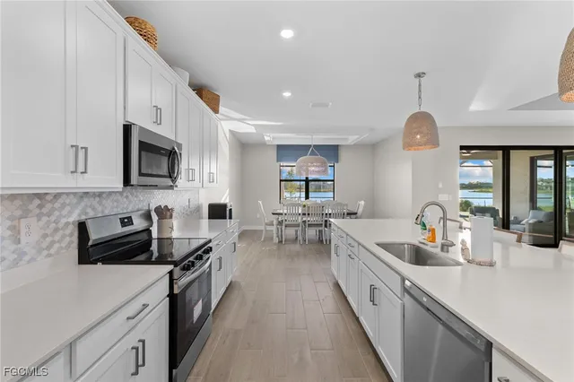 a large kitchen with stainless steel appliances granite countertop a lot of counter space a sink and dishwasher a stove top oven with wooden floor