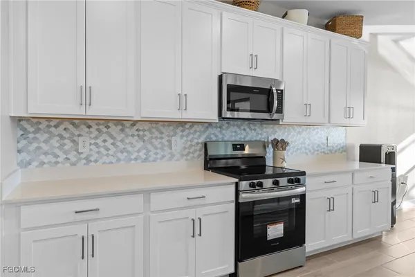 a kitchen with white cabinets and black appliances